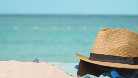 Summer-Holiday-Concept-Of-Sunglasses-Sun-Hat-Mobile-Phone-Beach-Towel-On-Sand-Against-Sea-1