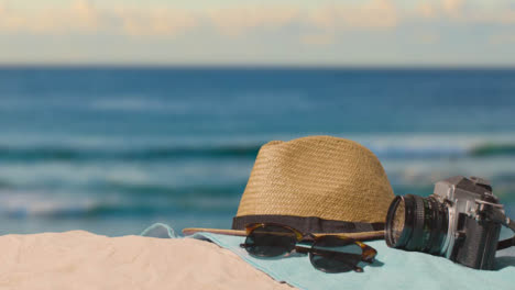 Summer-Holiday-Concept-Of-Camera-Sun-Hat-Sunglasses-Beach-Towel-On-Sand-Against-Sea-1