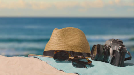 Summer-Holiday-Concept-Of-Camera-Sun-Hat-Sunglasses-Beach-Towel-On-Sand-Against-Sea-2