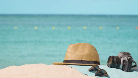 Summer-Holiday-Concept-Of-Camera-Sun-Hat-Sunglasses-Beach-Towel-On-Sand-Against-Sea-3