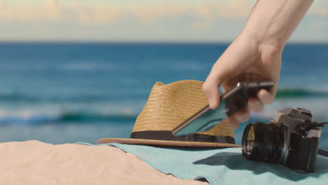 Summer-Holiday-Concept-Of-Camera-Sun-Hat-Mobile-Phone-Beach-Towel-On-Sand-Against-Sea-2