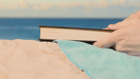 Concepto-De-Vacaciones-De-Verano-De-Una-Persona-En-Un-Libro-De-Lectura-De-Toallas-De-Playa-Contra-El-Fondo-Del-Mar