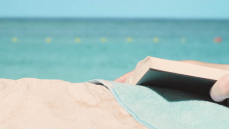 Summer-Holiday-Concept-Of-Person-On-Beach-Towel-Reading-Book-Against-Sea-Background-1