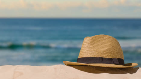 Sommerferienkonzept-Mit-Der-Hand,-Die-Sonnenhut-Auf-Sand-Gegen-Meereshintergrund-Aufhebt