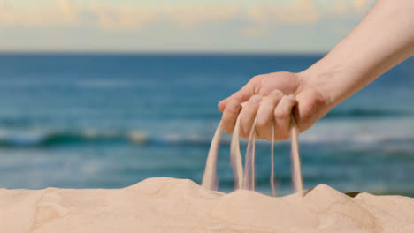 Summer-Holiday-Concept-With-Hand-Picking-Up-Sand-From-Beach-Against-Sea-Background-2