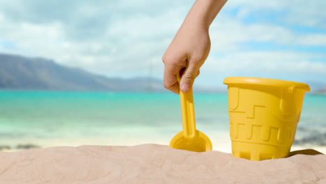 Summer-Holiday-Concept-With-Child's-Bucket-Spade-On-Sandy-Beach-Against-Sea-Background-1