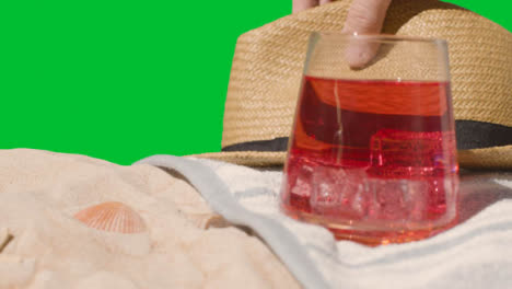 Summer-Holiday-Concept-Of-Cold-Drink-On-Beach-Towel-With-Sun-Hat-Against-Green-Screen-1