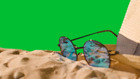 Sommerferienkonzept-Der-Sonnenbrille-Sonnenhut-Flip-Flops-Strandtuch-Auf-Sand-Gegen-Grünen-Bildschirm