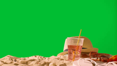 Sommerferienkonzept-Des-Kalten-Getränks-Auf-Strandtuch-Mit-Flip-flops-Sonnenbrille-Und-Sonnenhut-Gegen-Grünen-Bildschirm