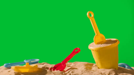 Summer-Holiday-Concept-With-Child's-Bucket-Spade-On-Sandy-Beach-Against-Green-Screen