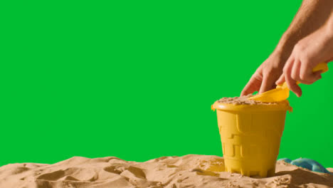Summer-Holiday-Concept-Making-Sandcastle-On-Sandy-Beach-Against-Green-Screen