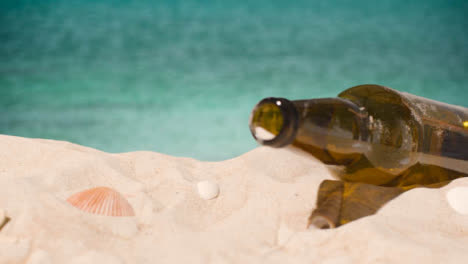 Pollution-Concept-With-Glass-Bottle-Being-Thrown-Onto-Beach-Against-Sea-Background