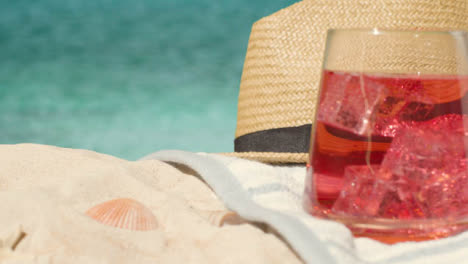 Summer-Holiday-Concept-Of-Cold-Drink-On-Beach-Towel-With-Sun-Hat-Against-Sea-Background-1