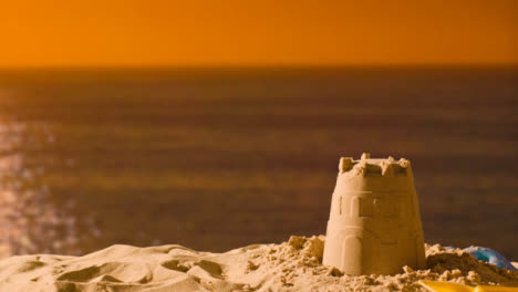 Summer-Holiday-Concept-Making-Sandcastle-On-Sandy-Beach-Against-Sea-And-Sunset-Sky-2