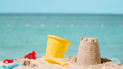 Summer-Holiday-Concept-Making-Sandcastle-On-Sandy-Beach-Against-Sea-Background