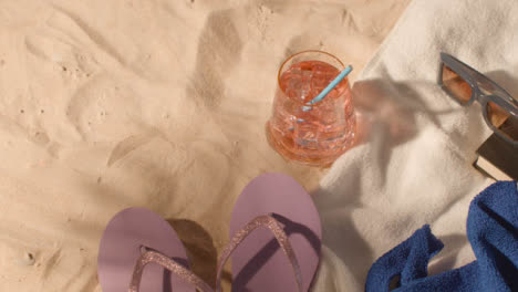 Summer-Holiday-Concept-Of-Cold-Drink-Sunglasses-Beach-Towel-Flip-Flops-Book-On-Sand