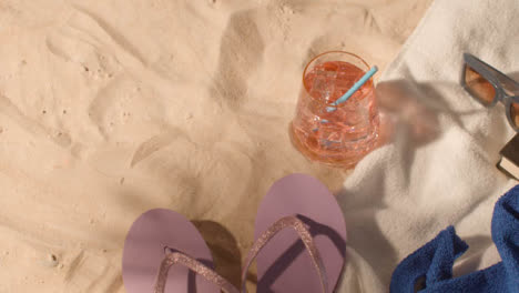 Summer-Holiday-Concept-Of-Cold-Drink-Sunglasses-Beach-Towel-Flip-Flops-Book-On-Sand-1
