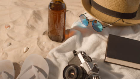 Sommerferienkonzept-Der-Bierflasche-Sonnenbrille-Strandtuch-Buch-Sonnenhut-Kamera-Auf-Sand