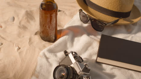 Sommerferienkonzept-Der-Bierflasche-Sonnenbrille-Strandtuch-Buch-Sonnenhut-Kamera-Auf-Sand-2