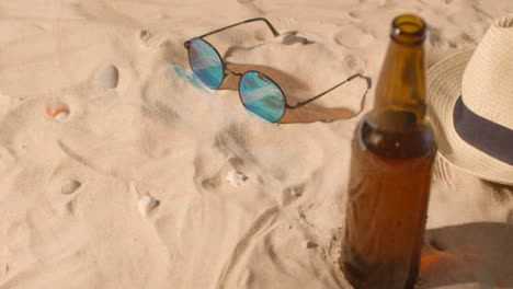 Sommerferienkonzept-Der-Bierflasche-Sonnenbrille-Strand-Sonnenhut-Auf-Sandhintergrund