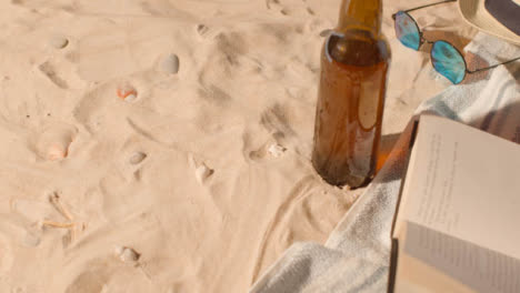 Sommerferienkonzept-Der-Bierflasche-Sonnenbrille-Strand-Sonnenhut-Buch-Auf-Sand