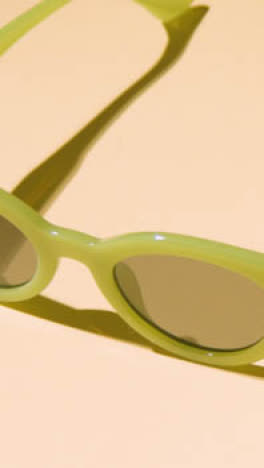 Vertical-Video-Summer-Holiday-Vacation-Concept-Of-Green-Sunglasses-On-Yellow-Background