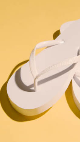 Vertical-Video-Summer-Holiday-Vacation-Concept-Of-Flip-Flops-Sandals-On-Yellow-Background