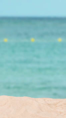 Vertical-Video-Summer-Holiday-Concept-With-Sandy-Beach-In-Foreground-Against-Sea-Background