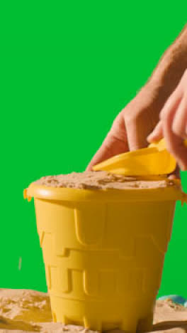 Vertical-Video-Summer-Holiday-Concept-Making-Sandcastle-On-Sandy-Beach-Against-Green-Screen