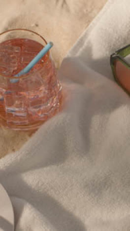 Vertical-Video-Summer-Holiday-Concept-Of-Flip-Flops-With-Cold-Drink-On-Sand-Background-With-Tree-Shade-Shadow-2