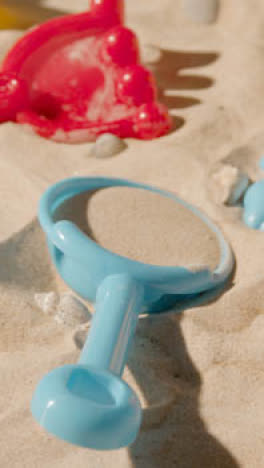 Vertical-Video-Summer-Holiday-Concept-With-Child's-Toys-Bucket-And-Spade-On-Sandy-Beach