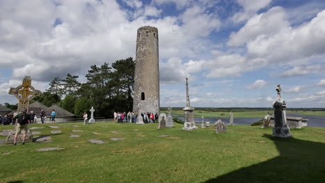 Irlanda-Clonmacnoise-Una-cruz-alta-y-un-grupo-de-turistas-en-una-torre-redonda