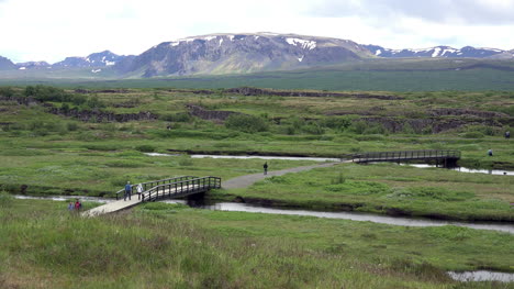 Island-Pingvellir-Leute-überqueren-Die-Brücke-über-Den-Bach