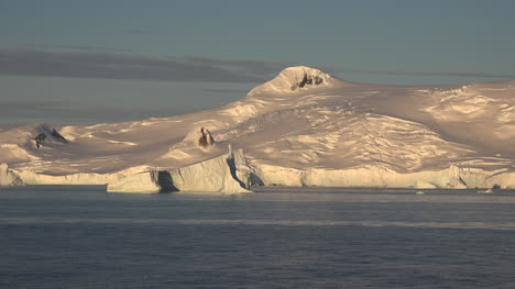 Antártida-Un-Iceberg-Y-Una-Montaña-Nevada-En-Luz-Dorada