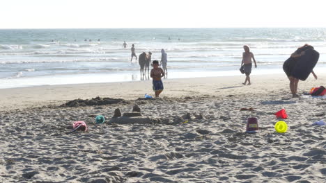 Los-Angeles-Venice-Beach-Woman-And-Boy-Walk-Past-Sandcastle-Remains