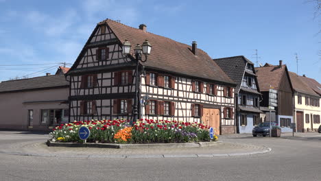 Francia-Alsacia-coche-pasa-tulipanes-y-casa-de-entramado-de-madera-en-Boofzheim