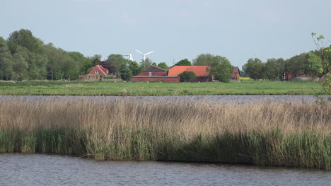 Germany-farmstead-and-wind-turbines-beyond-lake-and-reeds