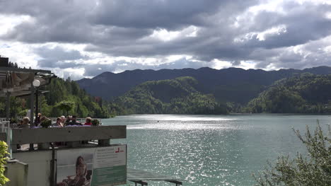 Slovenia-Bled-tourists-on-terrace-and-sun-on-Lake-Bled