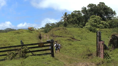 Maui-Hikers-walking-up-hill-past-fence