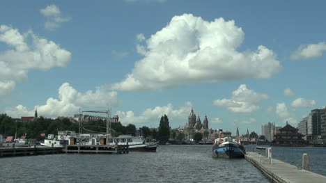 Netherlands-Amsterdam-dock-view-past-boats-to-church-spires