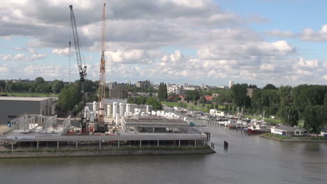 Netherlands-Rotterdam-trees-behind-boat-harbor-and-tall-cranes