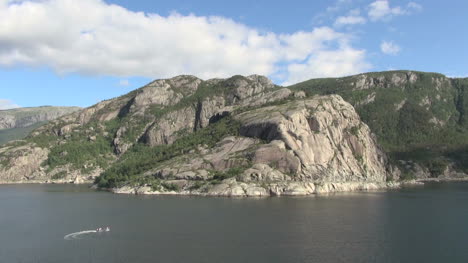 Norway-A-small-boat-turns-in-Lysefjord-below-mountainss