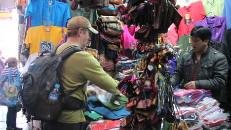 Peru-Cusco-man-in-cap-shops-at-vendor-booth