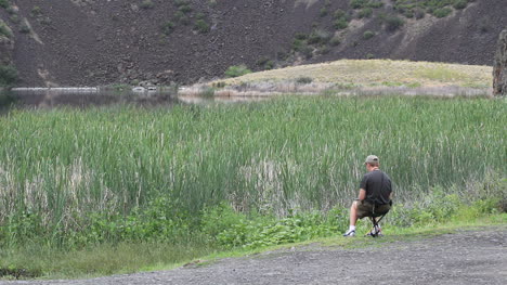 Washington-man-sits-near-marsh-and-gravel-slope