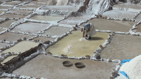 A-woman-works-to-pile-up-salt-in-a-salt-pan-in-the-Andes