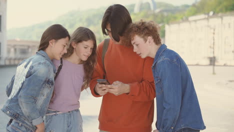 Un-Grupo-De-Adolescentes-Con-Dos-Chicas-Y-Dos-Chicos-Viendo-Algo-Divertido-En-Un-Teléfono-Celular