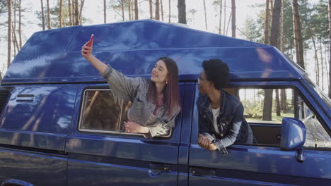 Two-Beautiful-Girls-Take-A-Selfie-Leaning-Out-Of-The-Window-Of-A-Caravan-During-A-Roadtrip-1