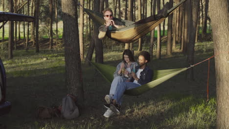 A-Multiethnic-Group-Of-Friends-Toasting-Happily-With-Their-Refreshments-Sitting-In-Their-Hammocks-In-The-Forest-1