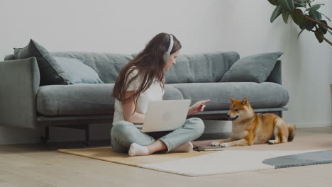 Pretty-Girl-Feeds-And-Pets-Her-Dog-While-Working-On-Her-Laptop-At-Home