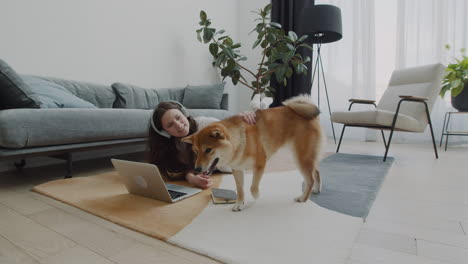 Mädchen-Spielt-Mit-Ihrem-Hund,-Während-Sie-Zu-Hause-An-Ihrem-Laptop-Arbeitet